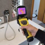 Technik z kamerą termowizyjną Trotec szuka wycieku wody pod płytkami w łazience.