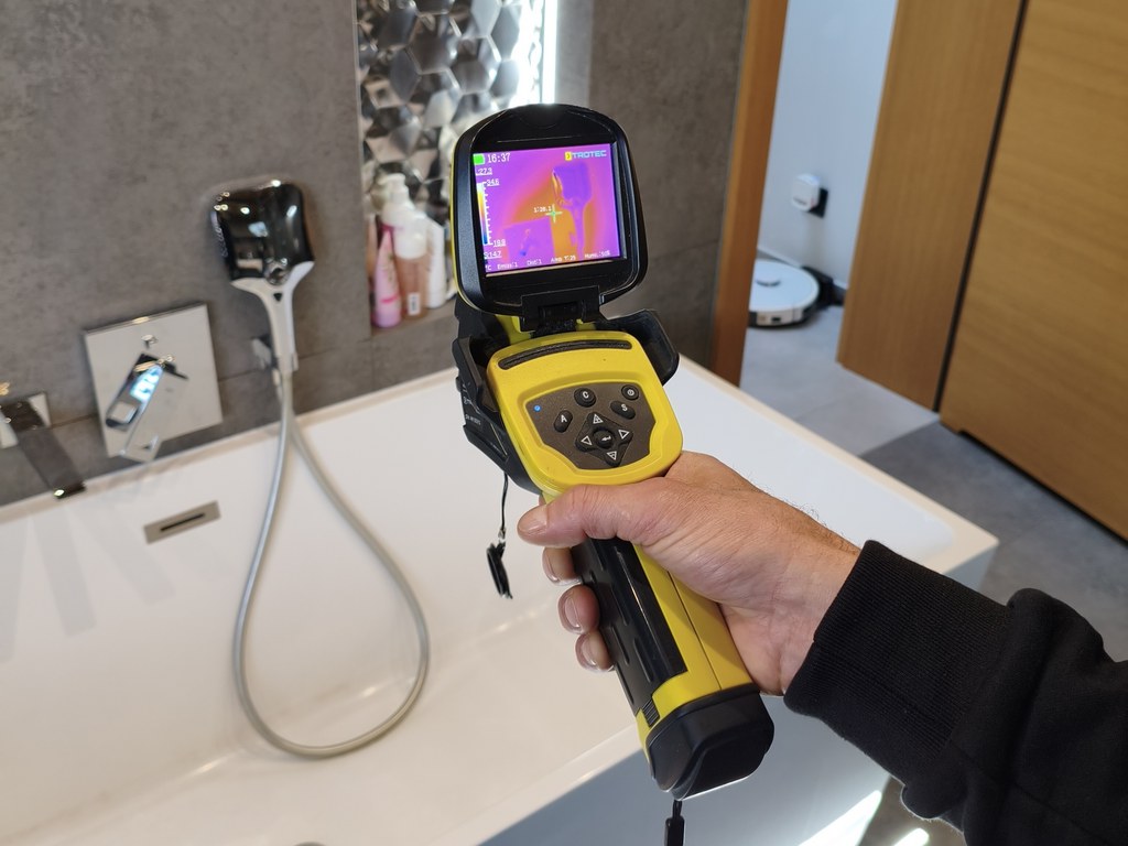 Technik z kamerą termowizyjną Trotec szuka wycieku wody pod płytkami w łazience.